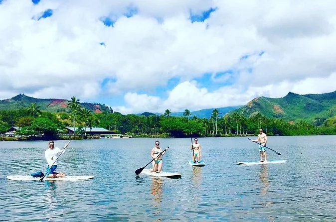 Four paddleboarders on a wide calm river with green hills behind